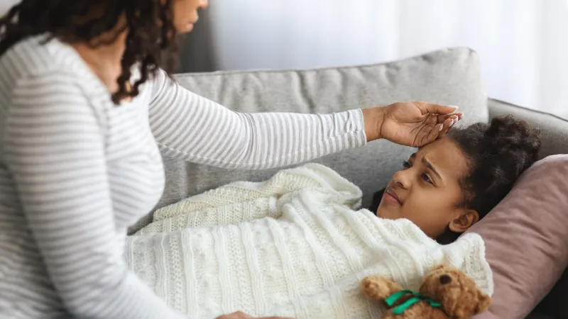 mother checking sick daughter body temperature
