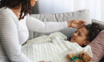 mother checking sick daughter body temperature