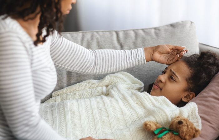 mother checking sick daughter body temperature